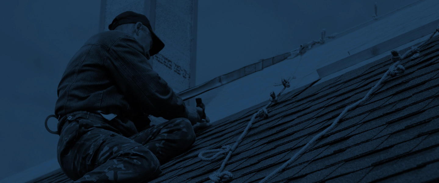 man with harness installing shingles on the roof 1